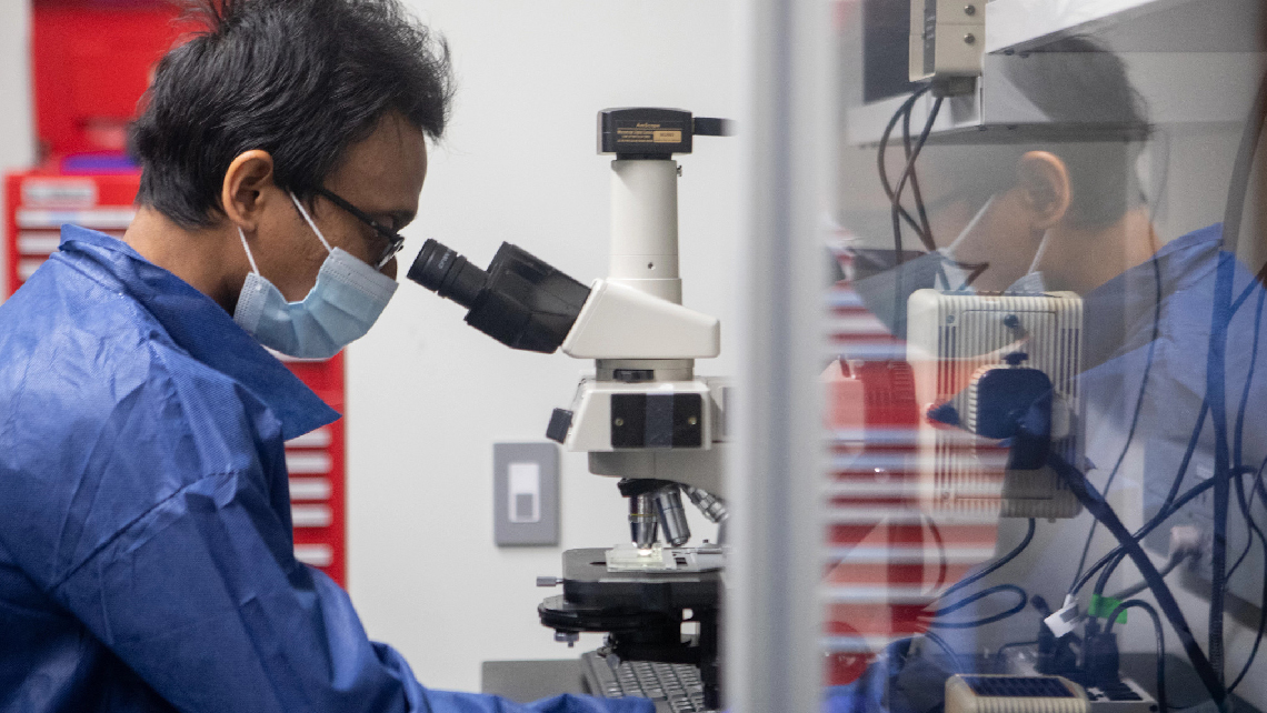 man in lab uses microscope